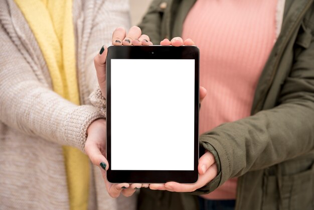 Dos chicas presentando mockup de tableta