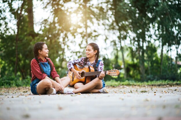 Dos chicas relajarse tocando la guitarra y cantar una canción