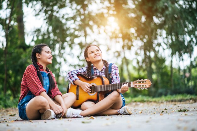 Dos chicas relajarse tocando la guitarra y cantar una canción