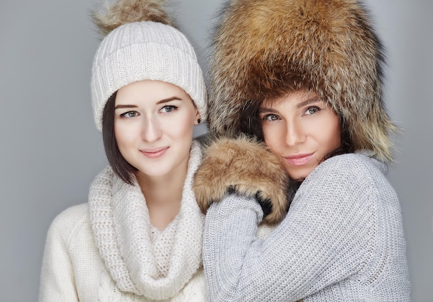 Dos chicas con ropa de invierno tomando fotos de selfie en un smartphone.