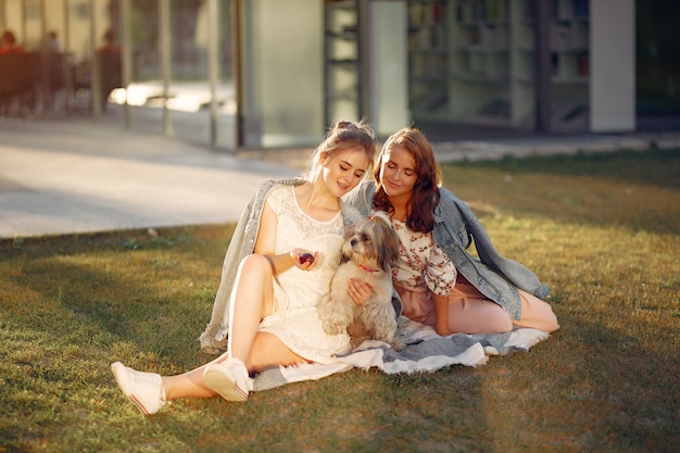 Foto gratuita dos chicas sentadas en un parque con un perrito