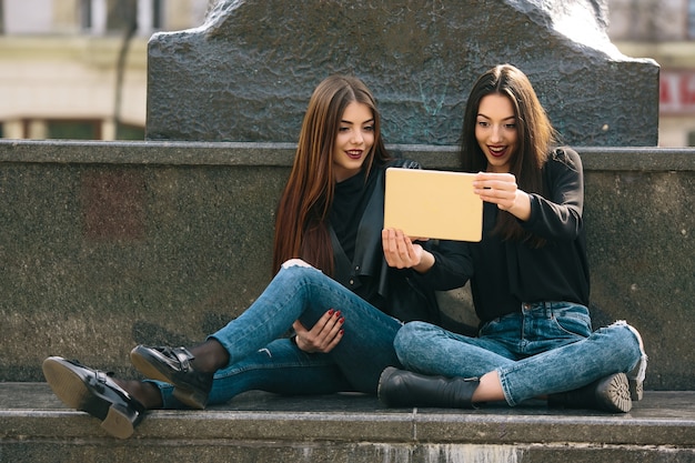 Dos chicas sentadas tomando una foto con una tablet