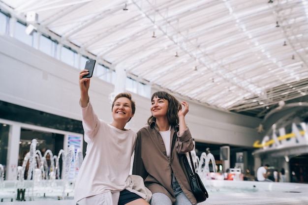 Dos chicas se toman una selfie en el centro comercial, una fuente