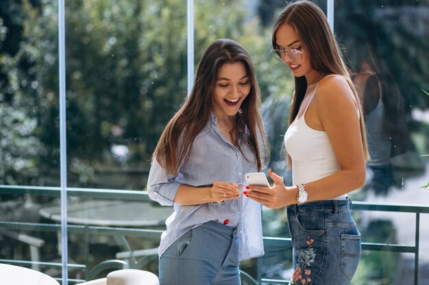 Dos chicas usando el teléfono en un café