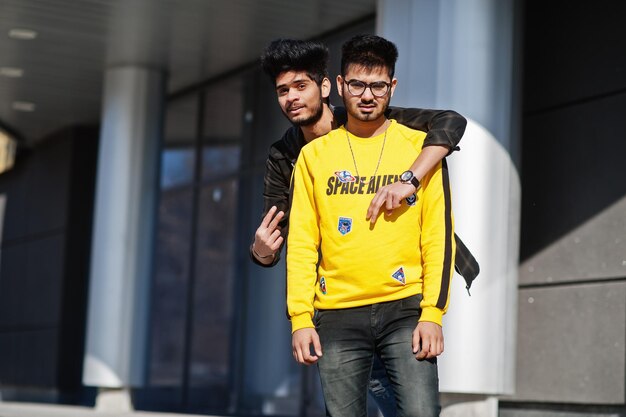 Dos chicos asiáticos posaron contra un nuevo edificio moderno