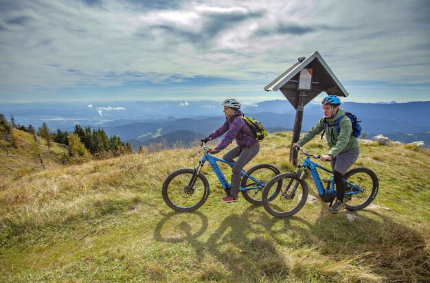 Dos ciclistas en la cima de una montaña con un hermoso entorno.