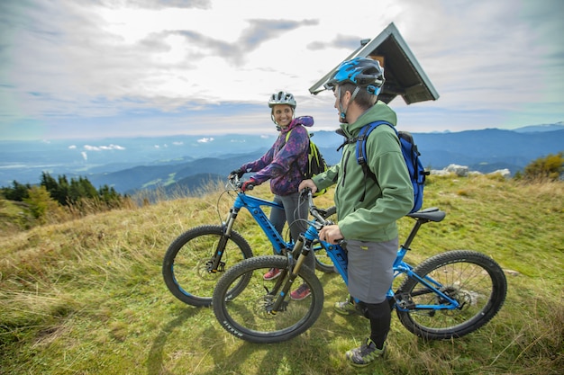 Dos ciclistas tomando un descanso en la cima de una montaña.