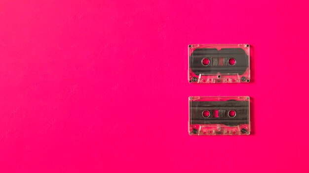 Dos cintas de cassette transparente sobre fondo rosa