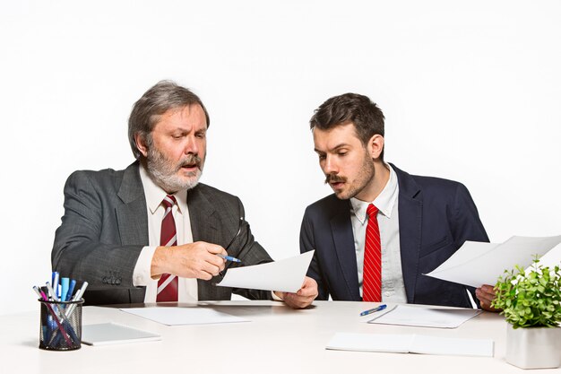 Los dos colegas que trabajan juntos en la oficina en el estudio blanco