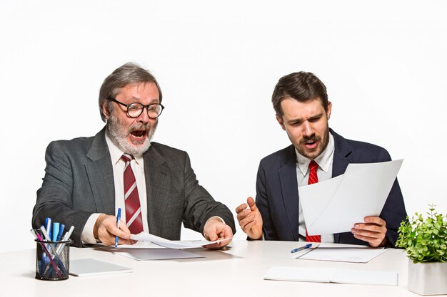 Los dos colegas que trabajan juntos en la oficina en el estudio blanco