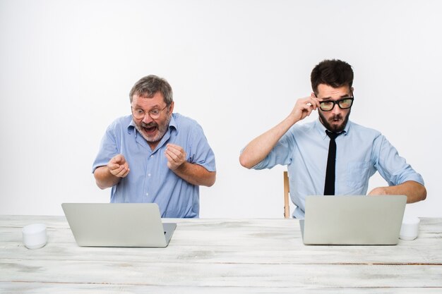 Los dos colegas que trabajan juntos en la oficina en la pared blanca