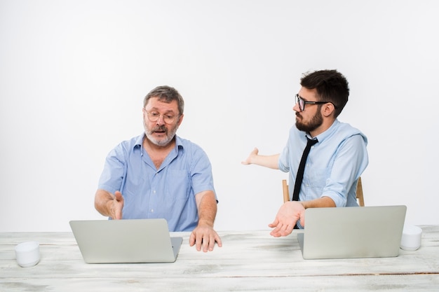 Los dos colegas que trabajan juntos en la oficina en la pared blanca