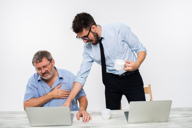 Los dos colegas que trabajan juntos en la oficina en la pared blanca