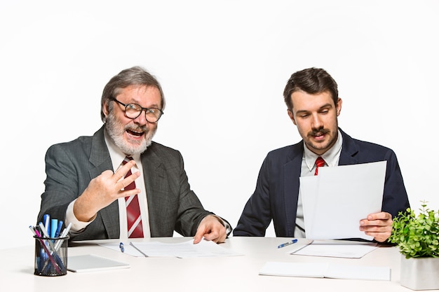 Los dos colegas que trabajan juntos en la oficina sobre fondo blanco. Discuten activa y emocionalmente los planes actuales.