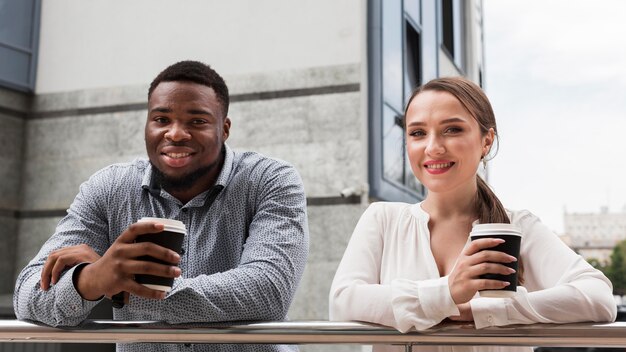 Dos colegas sonrientes tomando café juntos en el trabajo durante la pandemia