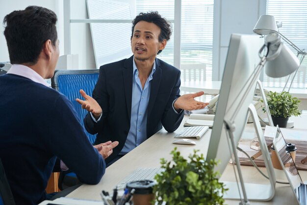 Dos colegas varones asiáticos discutiendo en la oficina