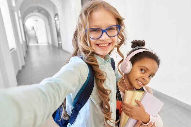 Foto gratuita dos colegialas rubias caucásicas y africanas haciendo selfie