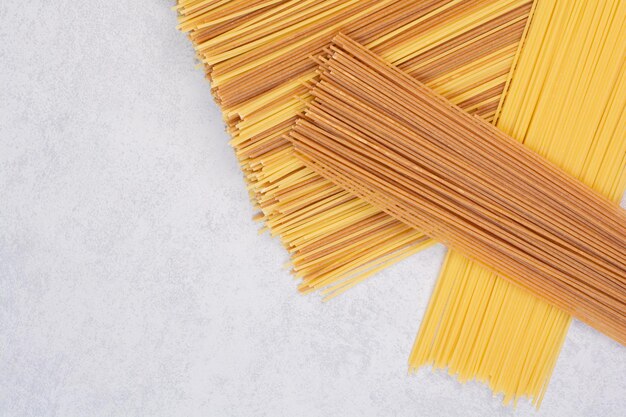 Dos colores de pasta de espagueti cruda en el cuadro blanco.