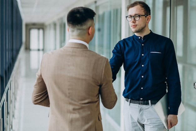 Dos compañeros masculinos dándose la mano en la oficina