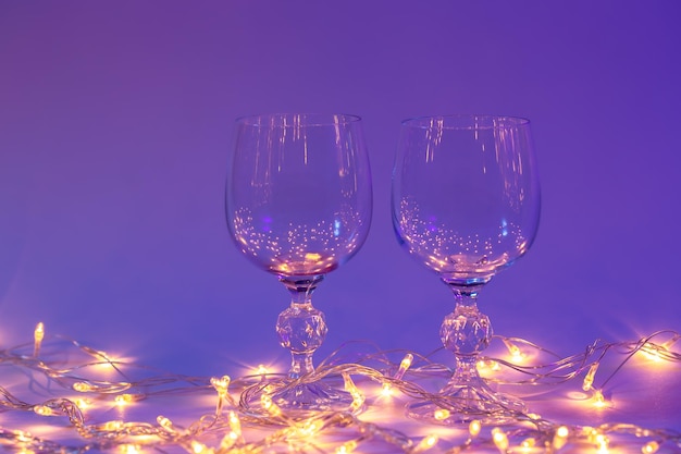 Dos copas de vino y una guirnalda con luces de neón Fondo del día de San Valentín