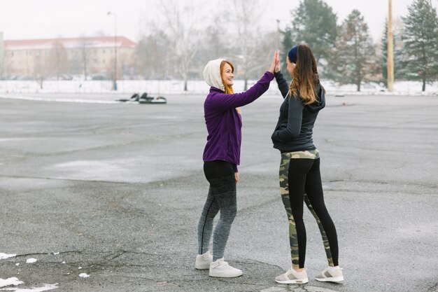 Dos corredores femeninos de pie en la calle dando alta cinco