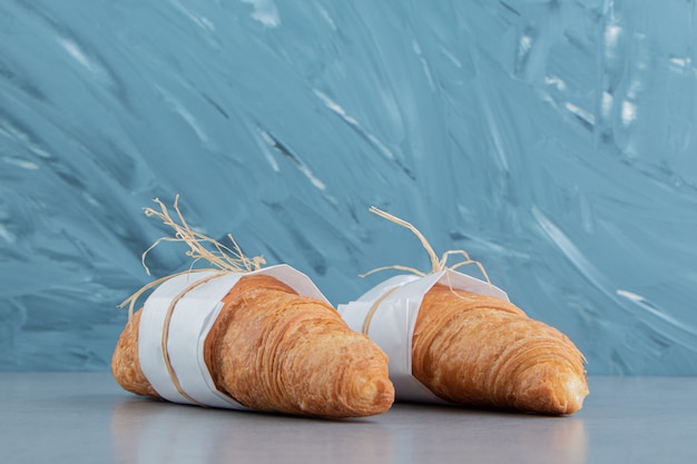 Dos croissants anudados en el fondo de mármol. Foto de alta calidad