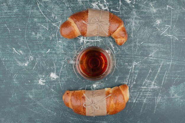 Dos croissants dulces con té caliente sobre mármol.