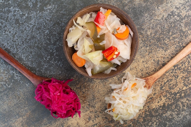 Dos cucharadas de repollo con cuenco de madera de verduras saladas. Foto de alta calidad