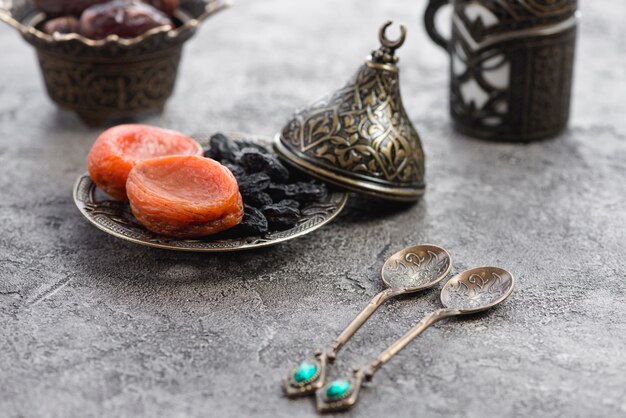 Dos cucharas metálicas tradicionales frente a albaricoque seco y pasas negras en un plato