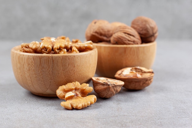 Dos cuencos de nueces enteras y agrietadas sobre fondo de mármol. Foto de alta calidad