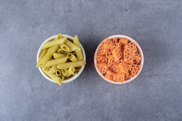 Dos cuencos de pasta varia sobre fondo de piedra.