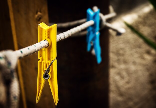 Dos diferentes clavos de lavado amarillo y azul colgando de la cuerda en el fondo de la vendimia.