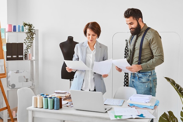 Dos diseñadores de moda trabajando en una nueva línea de ropa en el atelier