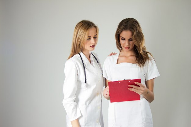 Dos doctores muy jóvenes de las mujeres, enfermeras que se colocan de nuevo a la parte posterior en el hospital.