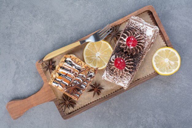 Dos dulces deliciosos trozos de pasteles con anís estrellado sobre tabla de madera.