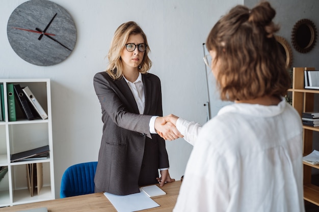 Dos empresarias dándose la mano en la oficina