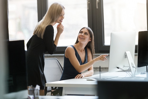 Dos empresarias sonrientes que trabajan juntas con la computadora