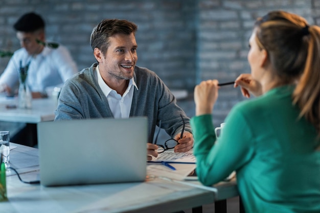 Foto gratuita dos empresarios hablando mientras trabajan en el escritorio de la oficina el foco está en el hombre de negocios feliz