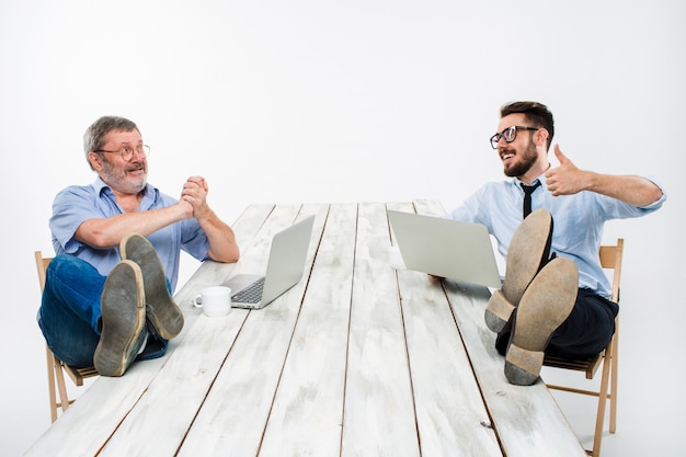 Dos empresarios con patas sobre la mesa trabajando en computadoras portátiles