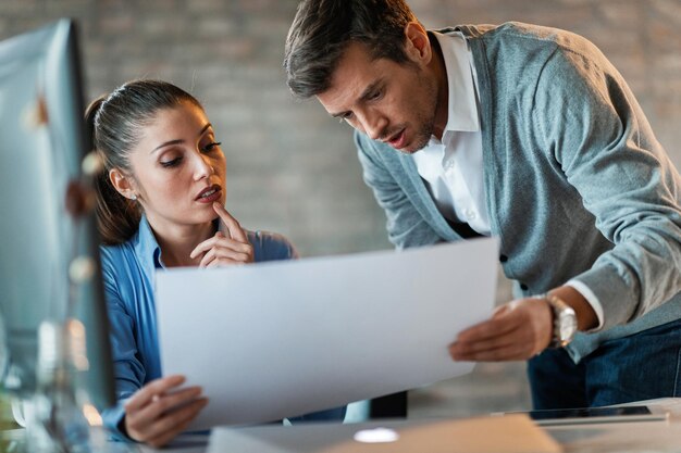 Dos empresarios que cooperan mientras leen planos y trabajan juntos en la oficina