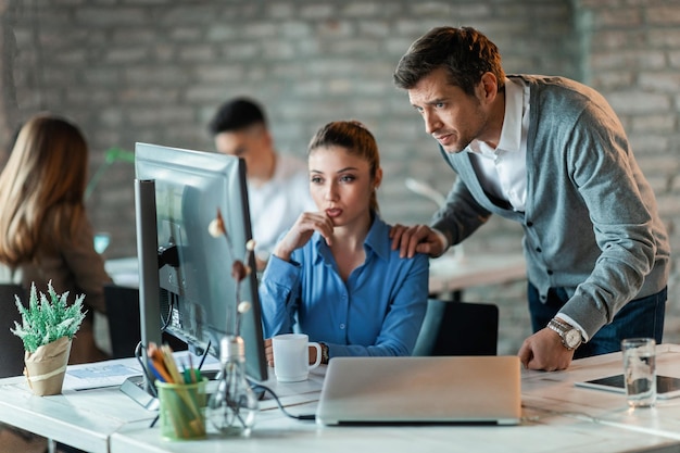 Dos empresarios que trabajan en la oficina y analizan planes de negocios en la computadora El foco está en el hombre