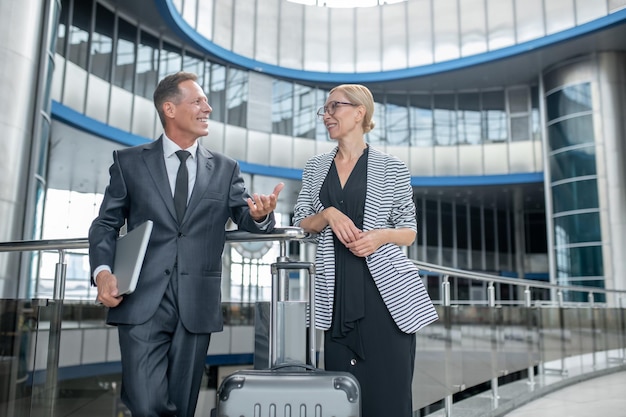 Dos empresarios sonrientes parados en la terminal del aeropuerto