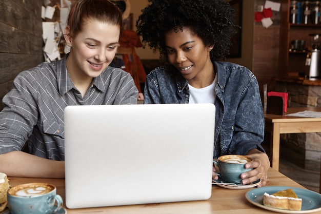 Dos estudiantes que trabajan en un proyecto universitario común usando una computadora portátil juntos en el café