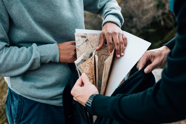 Dos excursionistas masculinos buscando mapa en la mochila