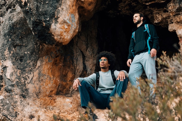 Dos excursionistas masculinos cerca de la entrada de la cueva