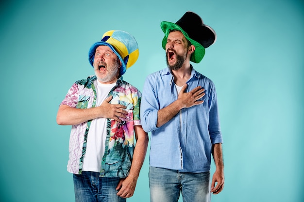 Los dos fanáticos del fútbol cantando el himno nacional sobre azul