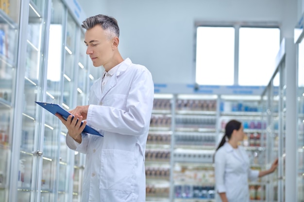 Dos farmacéuticos haciendo revisión de medicamentos en una farmacia.