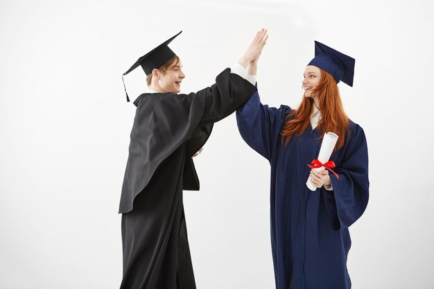 Dos felices graduados de la universidad que sonríen después de recibir diplomas que pronto serán abogados.