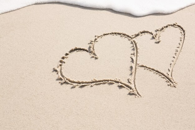 Dos formas de corazón dibujado en la arena
