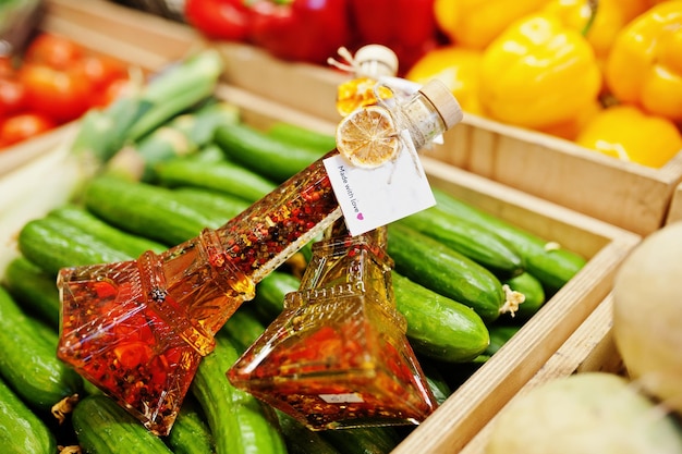 Dos frascos de aceite de oliva virgen con condimentos en botella como la torre Eifel en el estante con pepinos en el supermercado o tienda de comestibles Hecho con amor